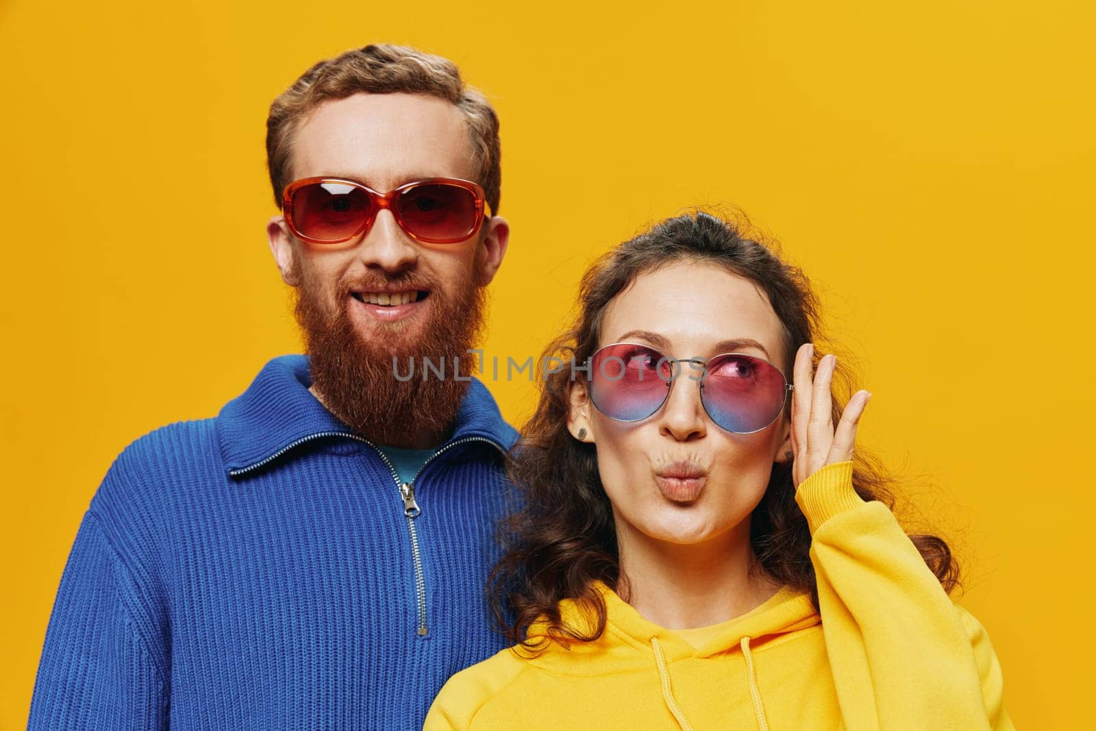 Man and woman couple smiling cheerfully and crooked with glasses, on yellow background, symbols signs and hand gestures, family shoot, newlyweds. High quality photo