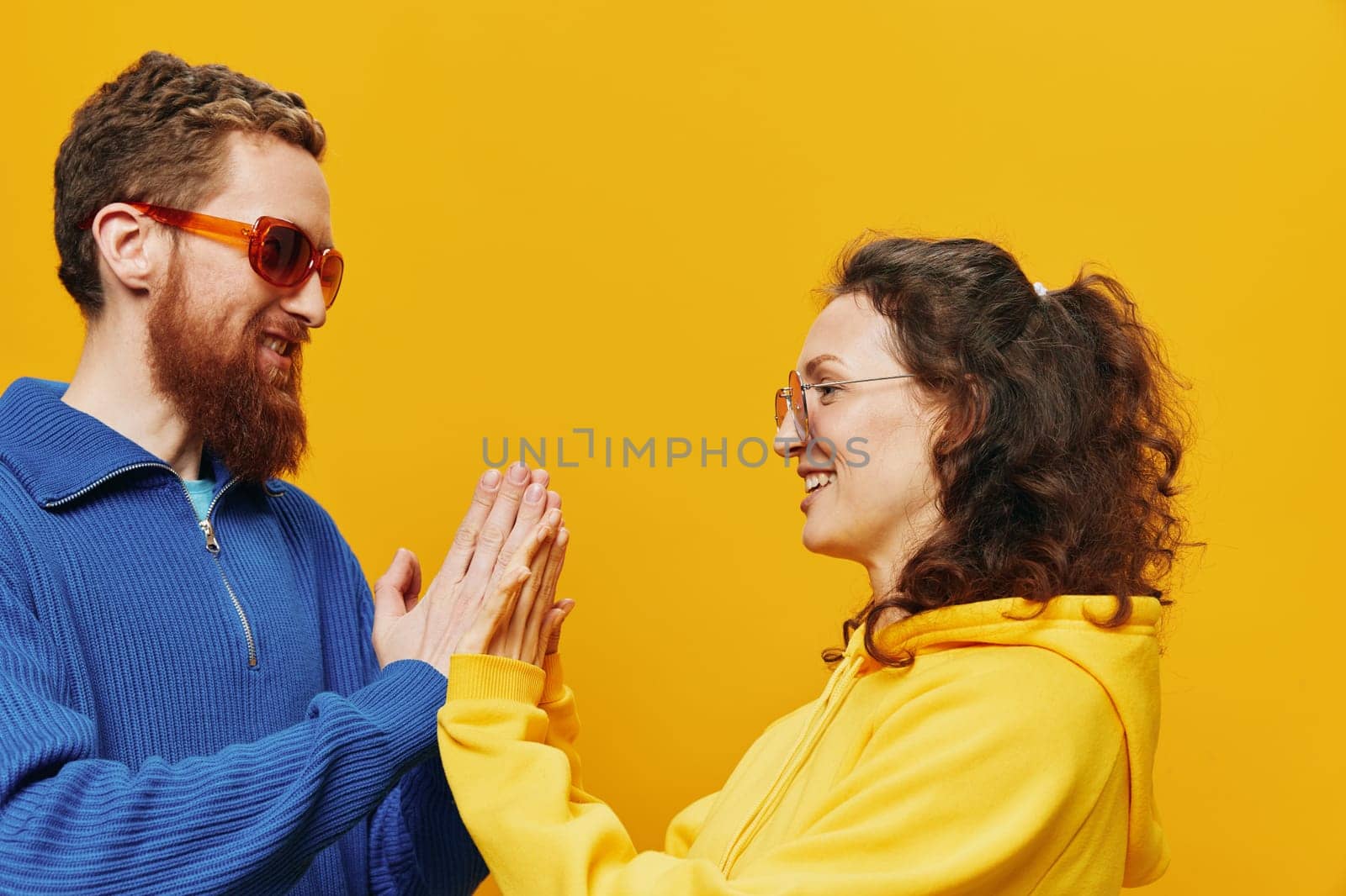 Man and woman couple smiling cheerfully and crooked with glasses, on yellow background, symbols signs and hand gestures, family shoot, newlyweds. by SHOTPRIME