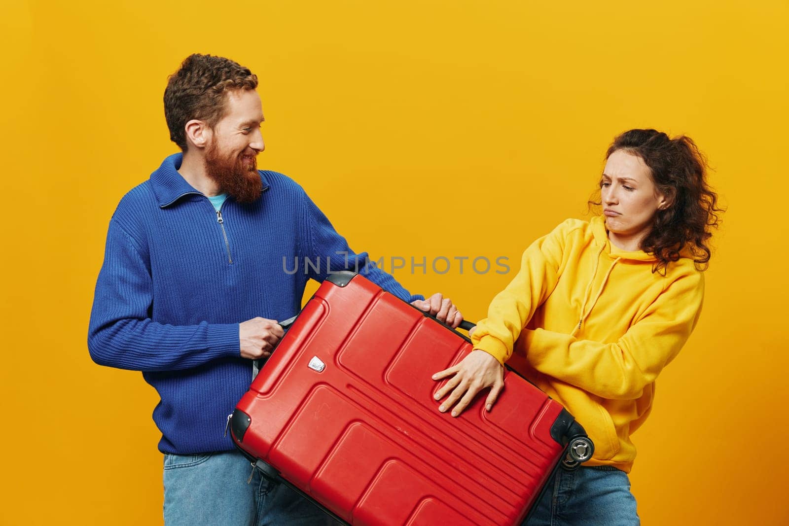 Woman and man smiling, suitcases in hand with yellow and red suitcase smiling merrily and crooked, yellow background, going on a trip, family vacation trip, newlyweds. by SHOTPRIME