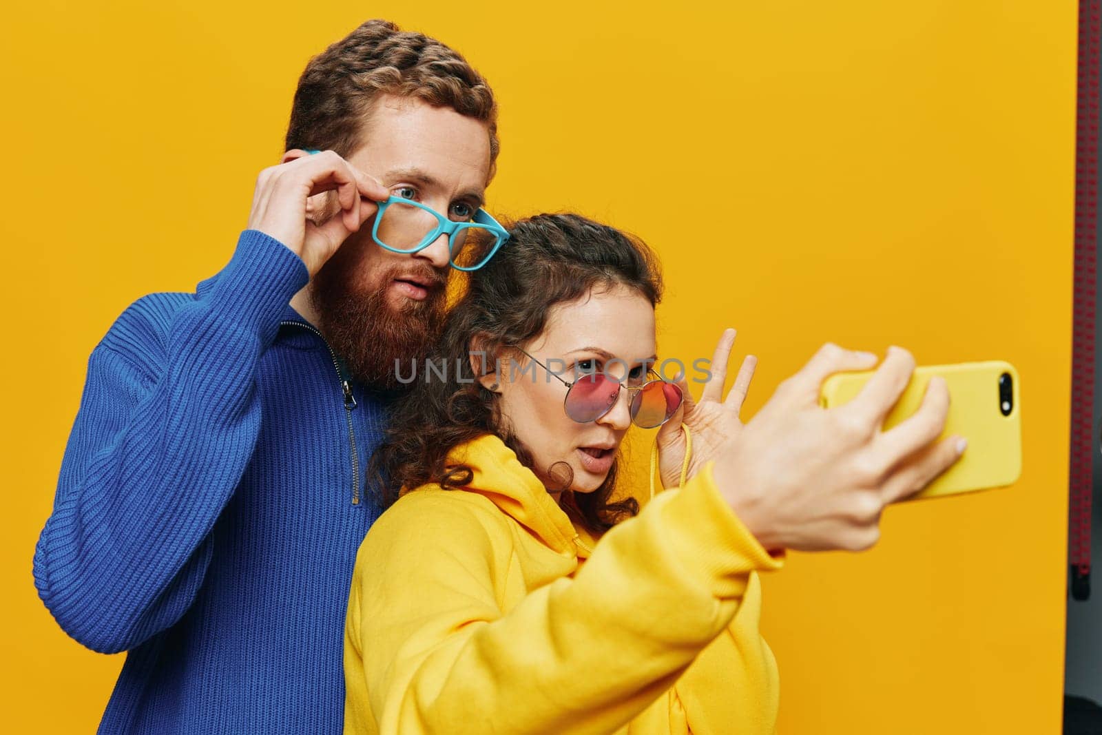 Woman and man funny couple with phones hand social networking and communication crooked do selfies smile fun, on yellow background. The concept of real family relationships, freelancers, work online. by SHOTPRIME