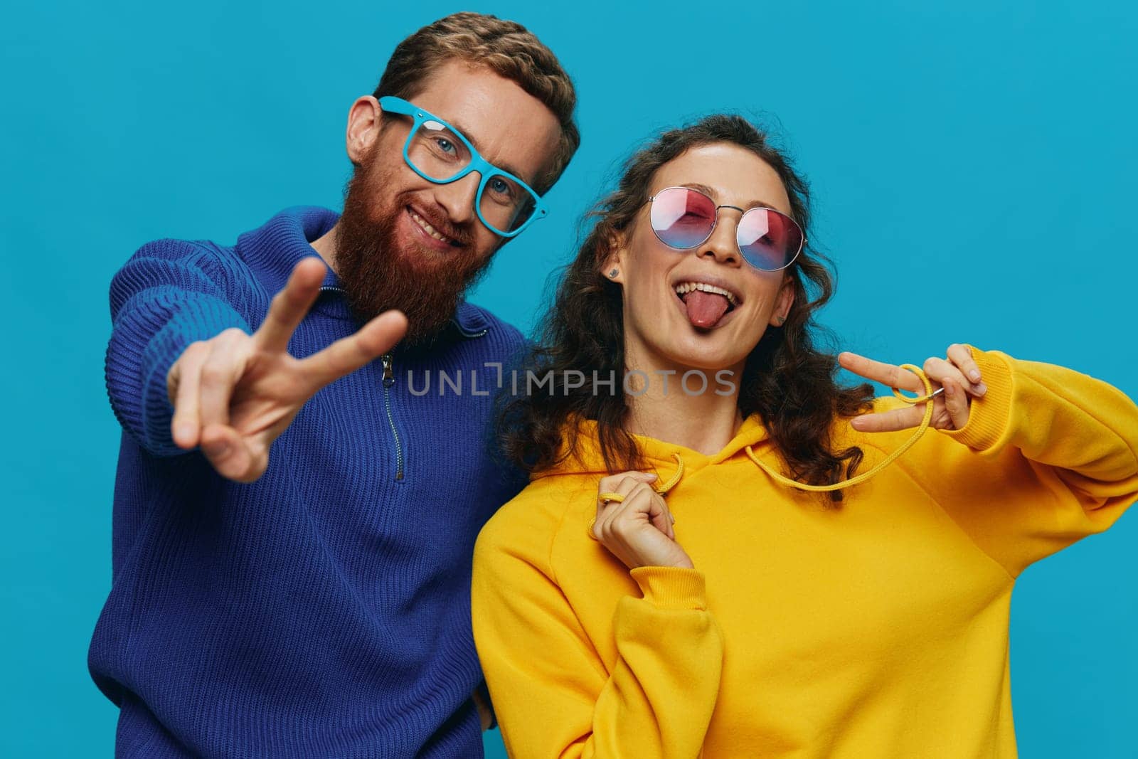 A woman and a man fun couple cranking and showing signs with their hands smiling cheerfully, on a blue background, The concept of a real relationship in a family. High quality photo