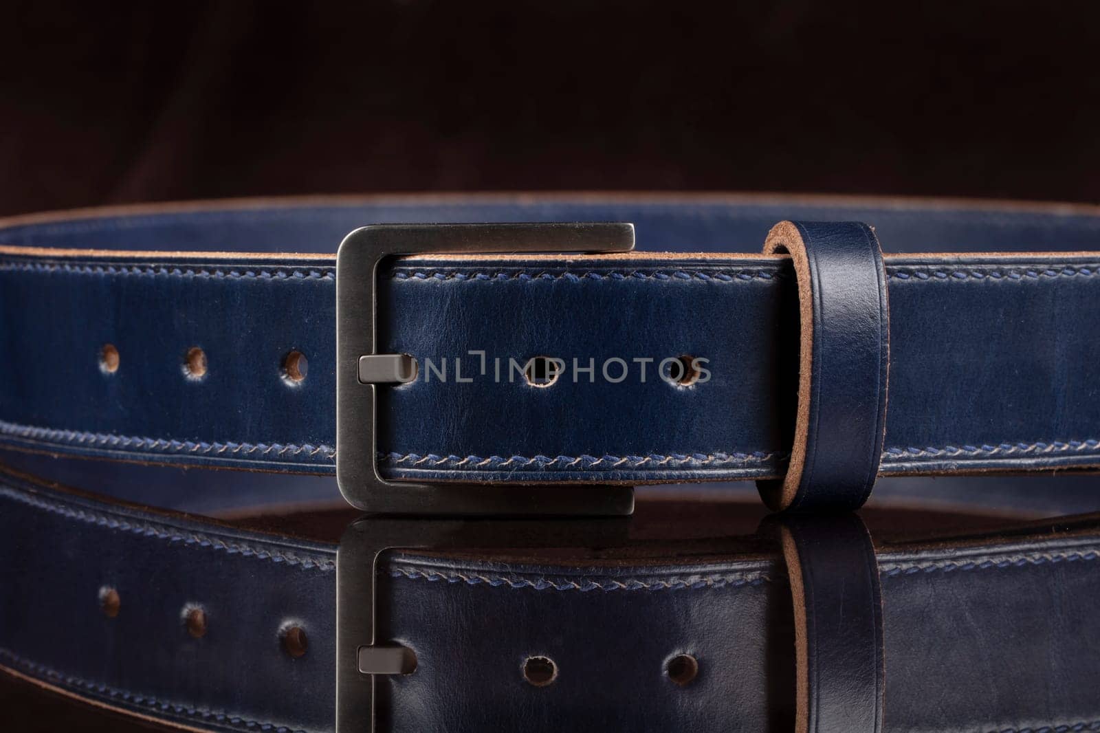 Part of a blue leather belt on a black background. by Sviatlana