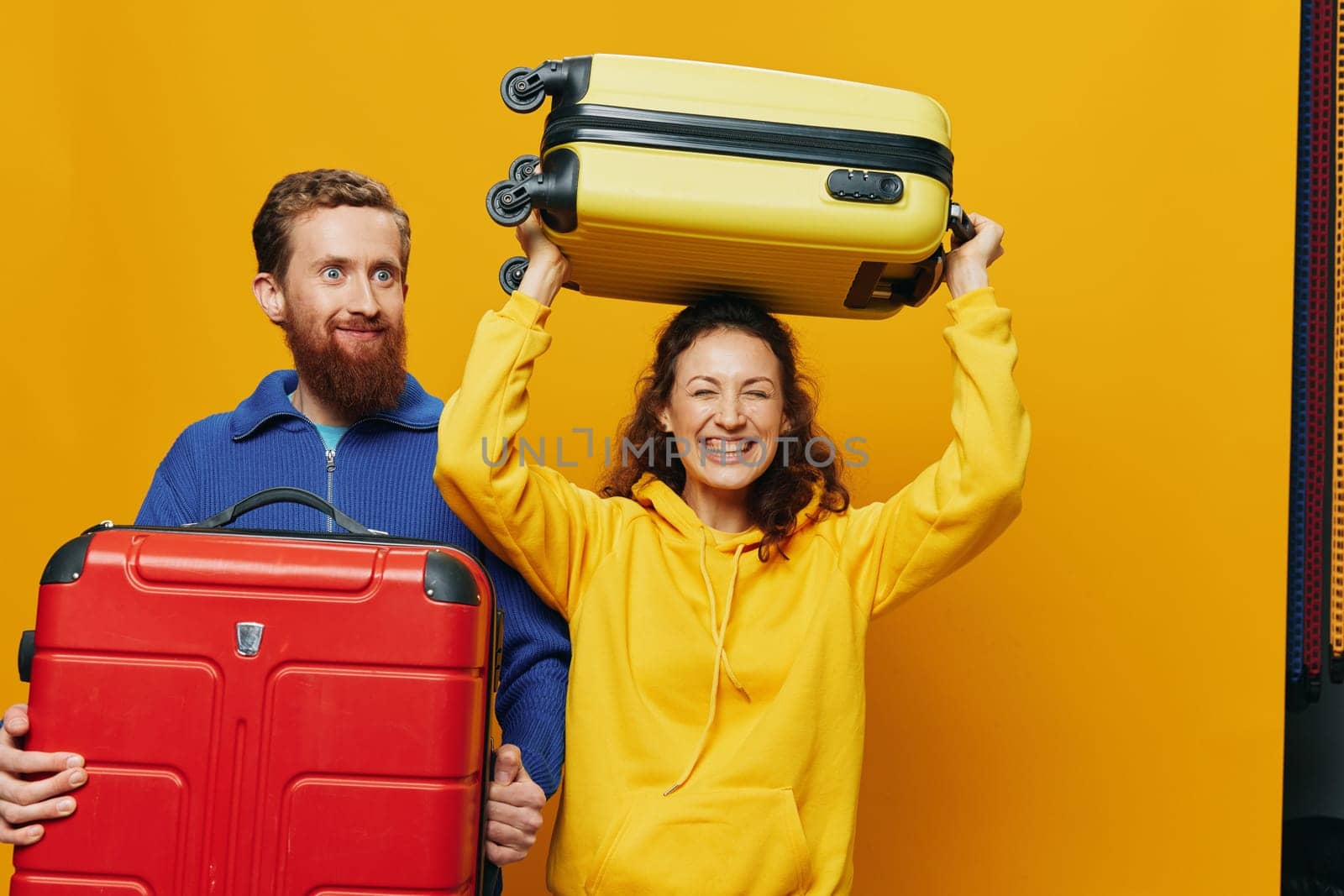 Woman and man smiling, suitcases in hand with yellow and red suitcase smiling merrily and crooked, yellow background, going on a trip, family vacation trip, newlyweds. by SHOTPRIME