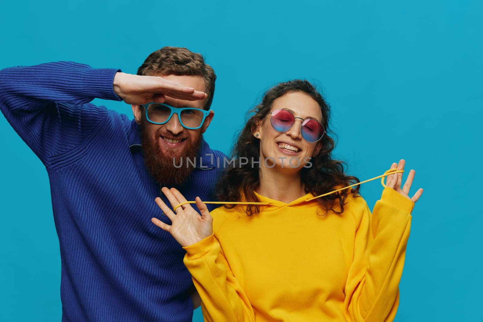 A woman and a man fun couple cranking and showing signs with their hands smiling cheerfully, on a blue background, The concept of a real relationship in a family. High quality photo