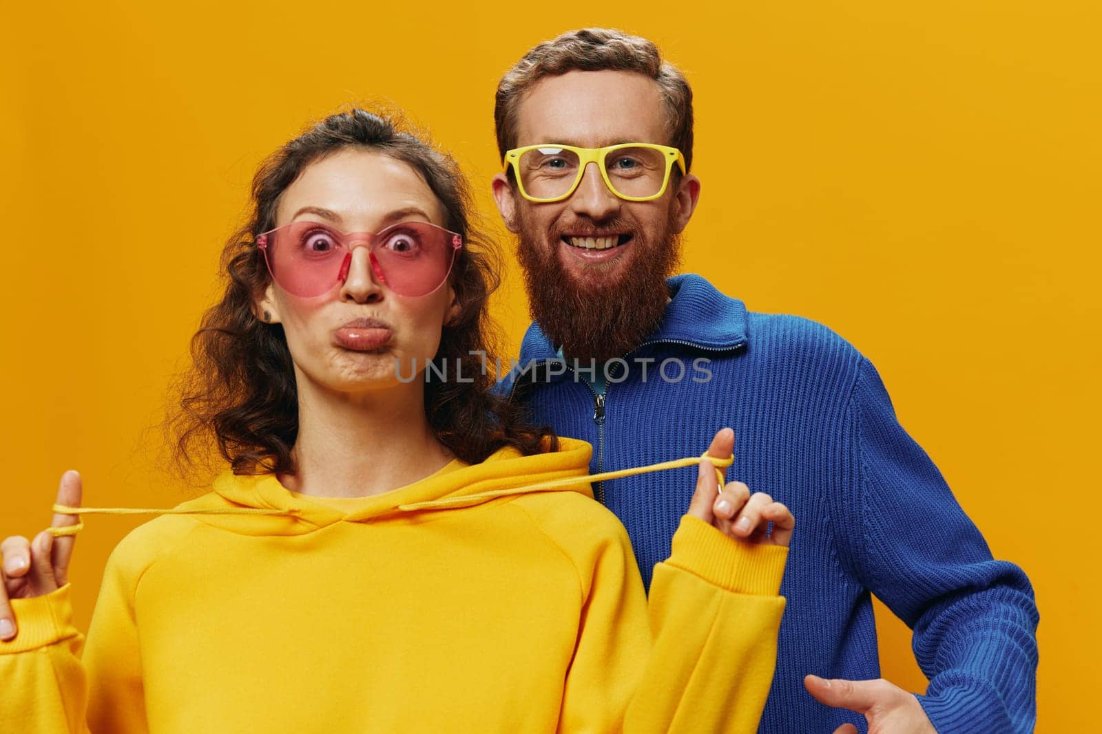 Man and woman couple smiling cheerfully and crooked with glasses, on yellow background, symbols signs and hand gestures, family shoot, newlyweds. High quality photo