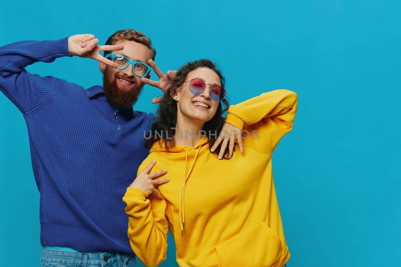 A woman and a man fun couple cranking and showing signs with their hands smiling cheerfully, on a blue background, The concept of a real relationship in a family. High quality photo