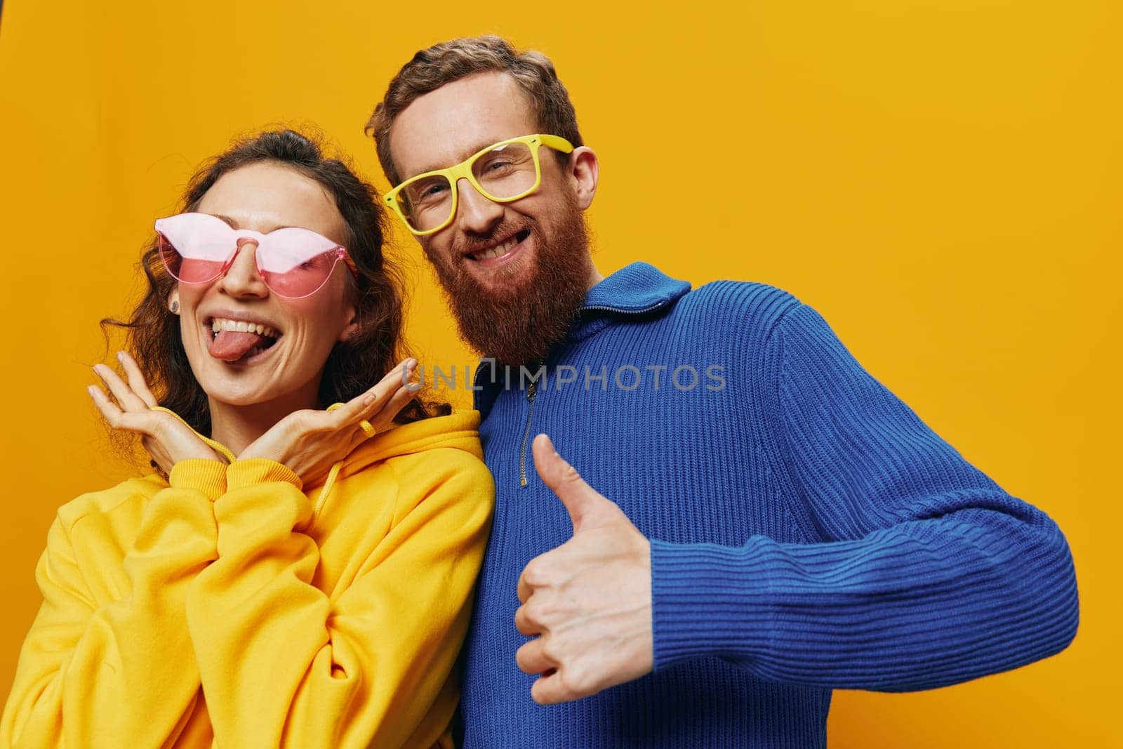 Man and woman couple smiling cheerfully and crooked with glasses, on yellow background, symbols signs and hand gestures, family shoot, newlyweds. High quality photo