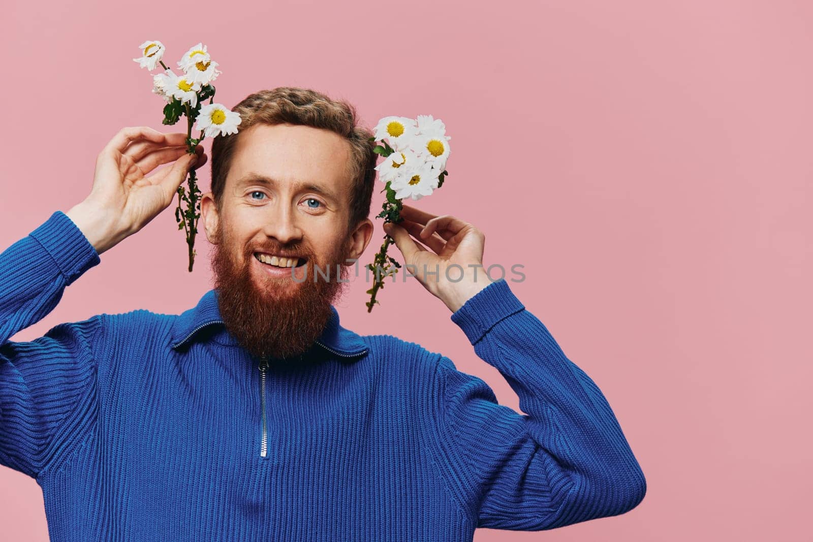 Portrait of a funny man smiling with a bouquet of flowers daisies on pink isolated background, copy place. Holiday concept and congratulations, Valentine's Day, Women's Day. High quality photo