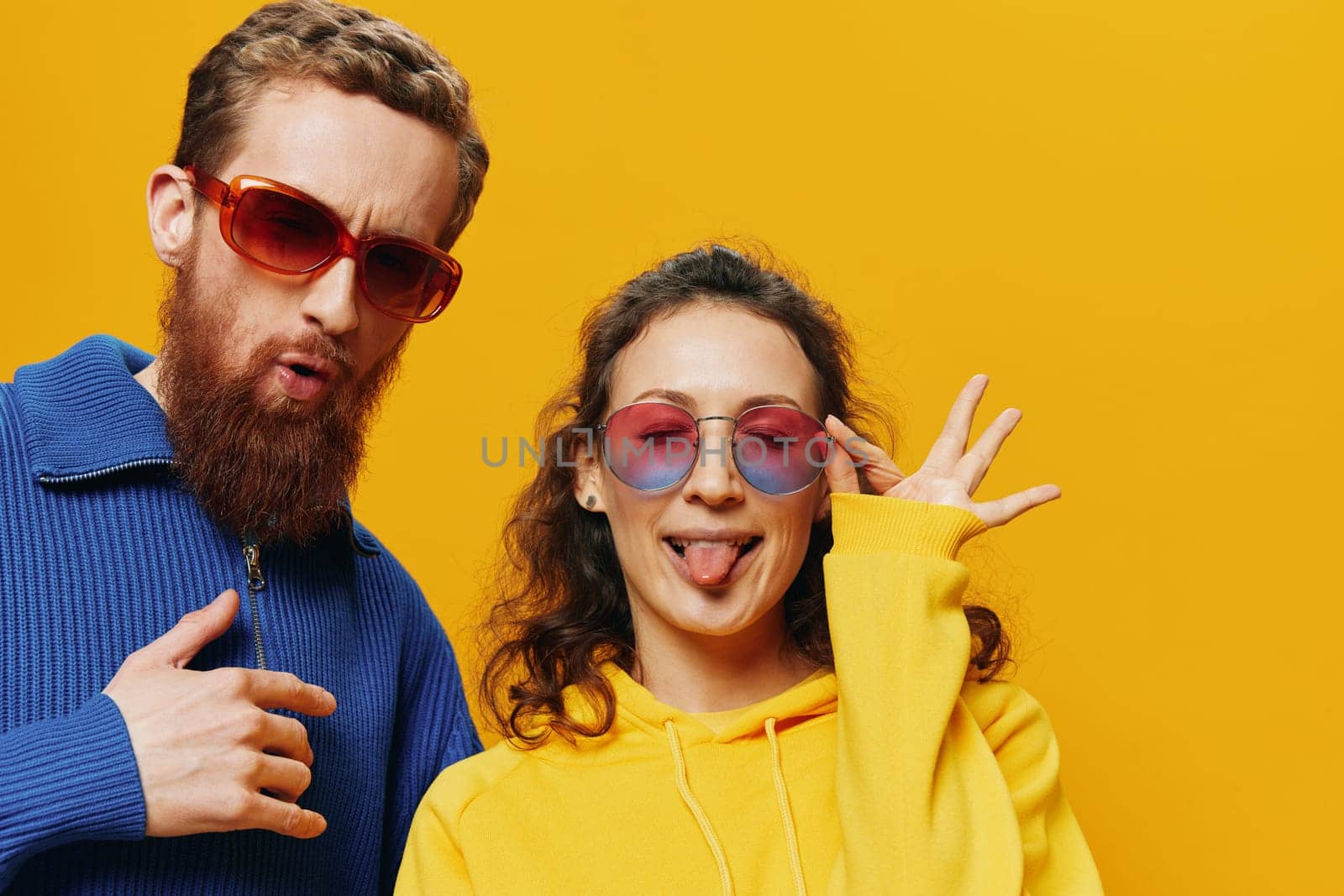 Man and woman couple smiling cheerfully and crooked with glasses, on yellow background, symbols signs and hand gestures, family shoot, newlyweds. High quality photo