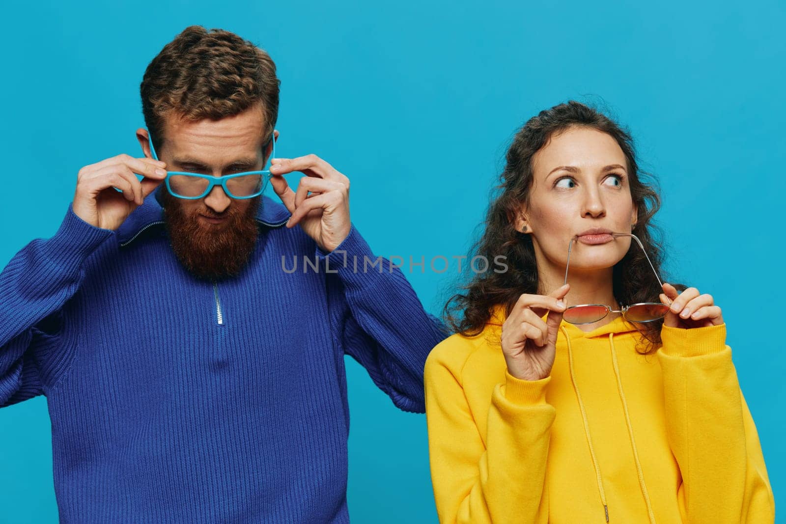 A woman and a man fun couple cranking and showing signs with their hands smiling cheerfully, on a blue background, The concept of a real relationship in a family. by SHOTPRIME