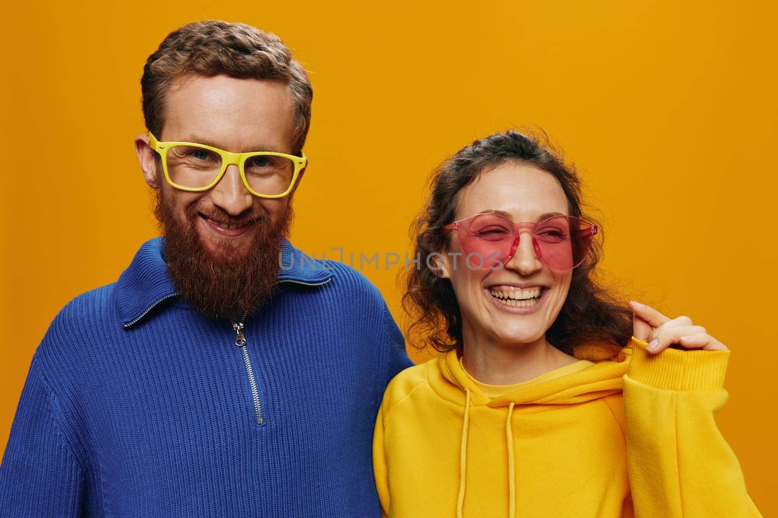 Man and woman couple smiling cheerfully and crooked with glasses, on yellow background, symbols signs and hand gestures, family shoot, newlyweds. High quality photo