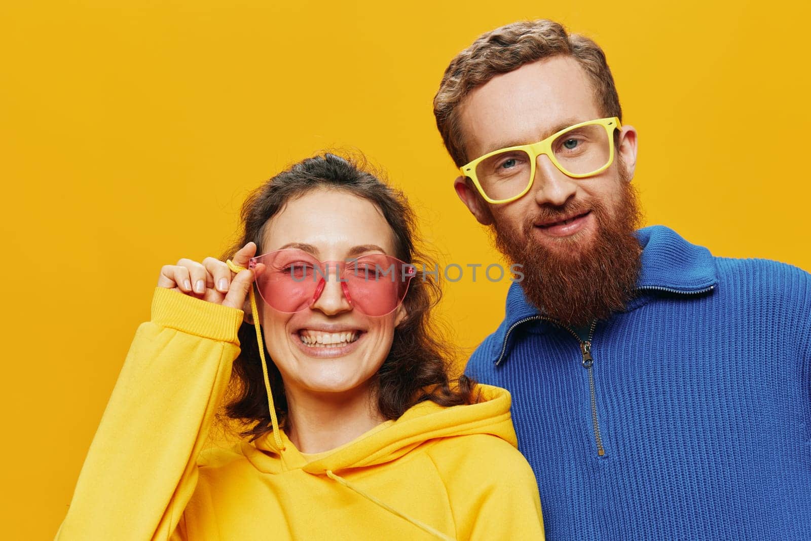 Man and woman couple smiling cheerfully and crooked with glasses, on yellow background, symbols signs and hand gestures, family shoot, newlyweds. High quality photo