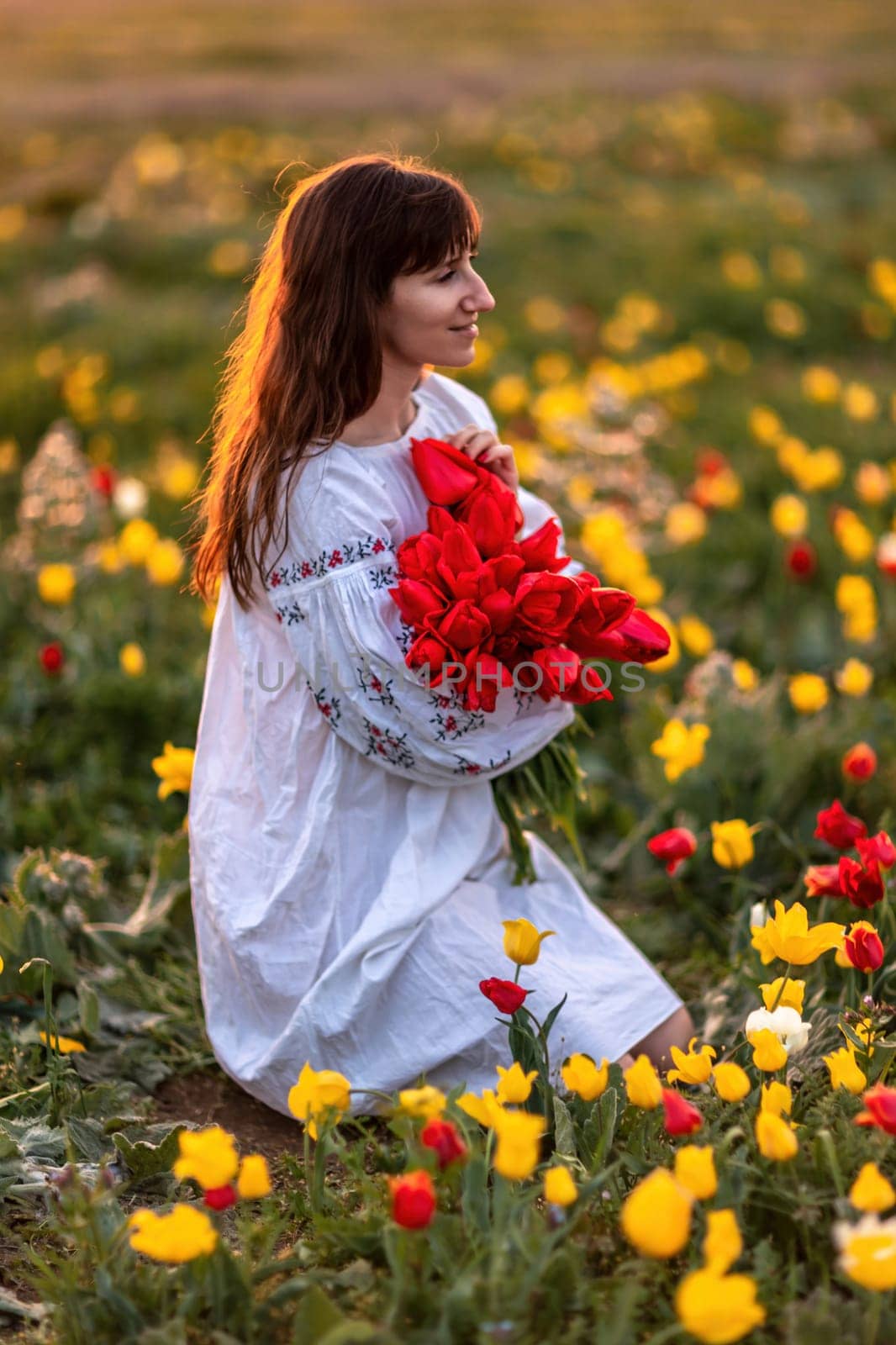 Woman field tulips sunset. Woman against sunset and wild tulip flowers, natural seasonal background. Multi-colored tulips Tulipa schrenkii in their natural habitat are listed in the Red Book. by Matiunina