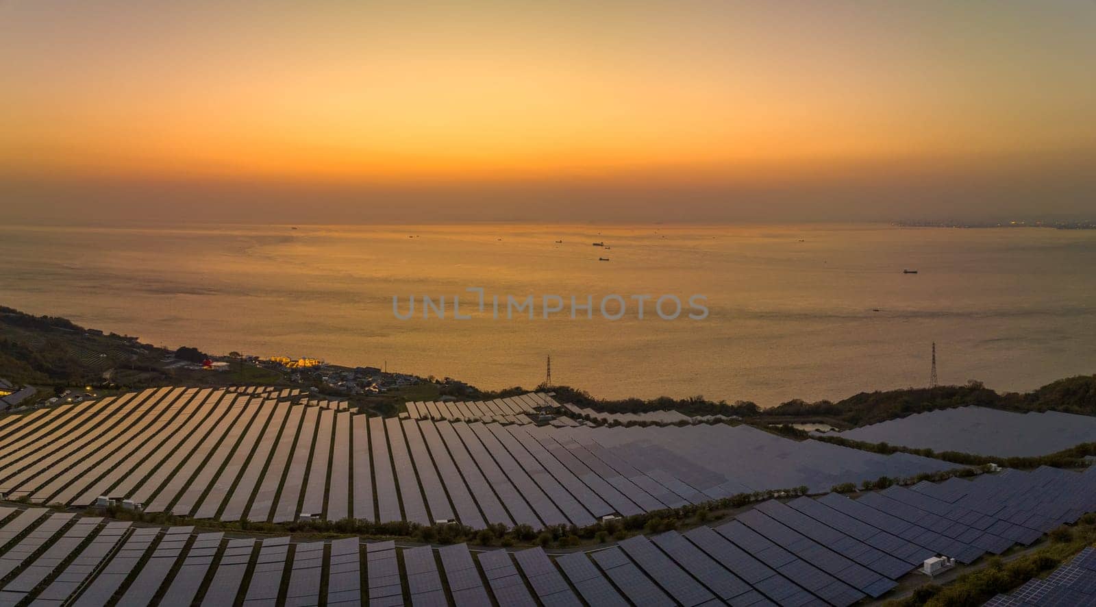 Sunset glow reflects off solar panels at coastal energy farm. High quality photo