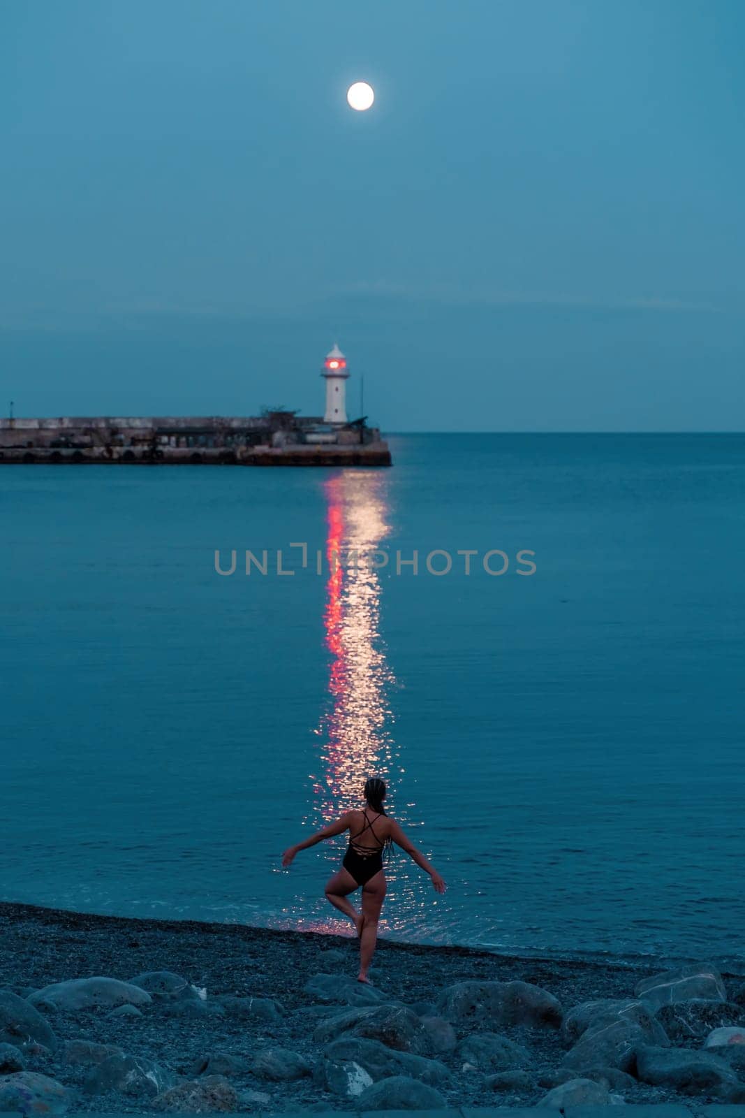 Woman The full moon rises to the lighthouse, the lunar path along the sea leads to the woman. by Matiunina