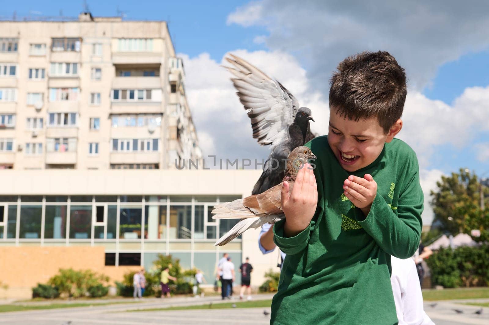 Teenage boy feeding rock pigeons outdoors. The concept of kindness, love and care for animals by artgf