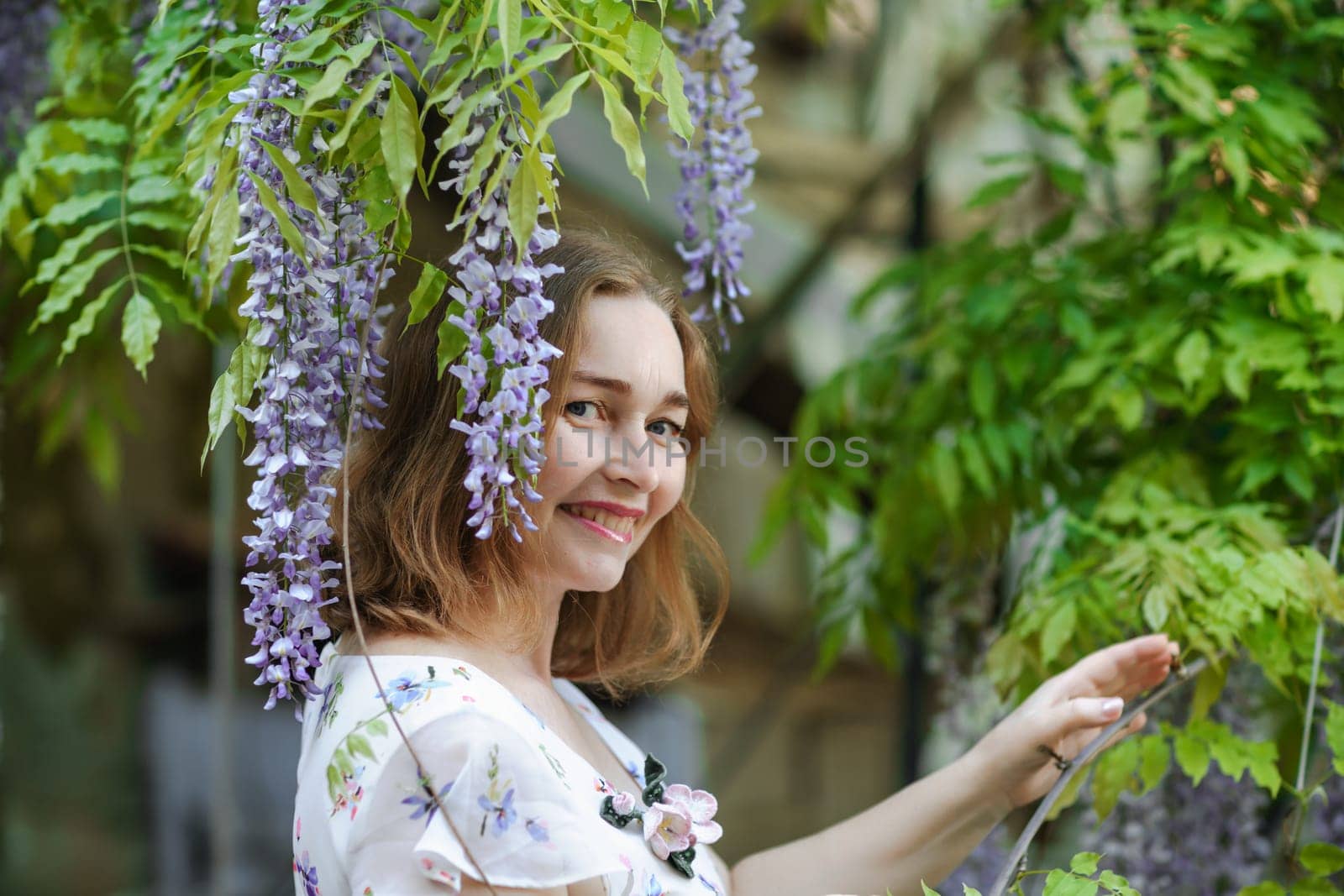 Wisteria woman. Thoughtful happy mature woman surrounded by chinese wisteria by Matiunina