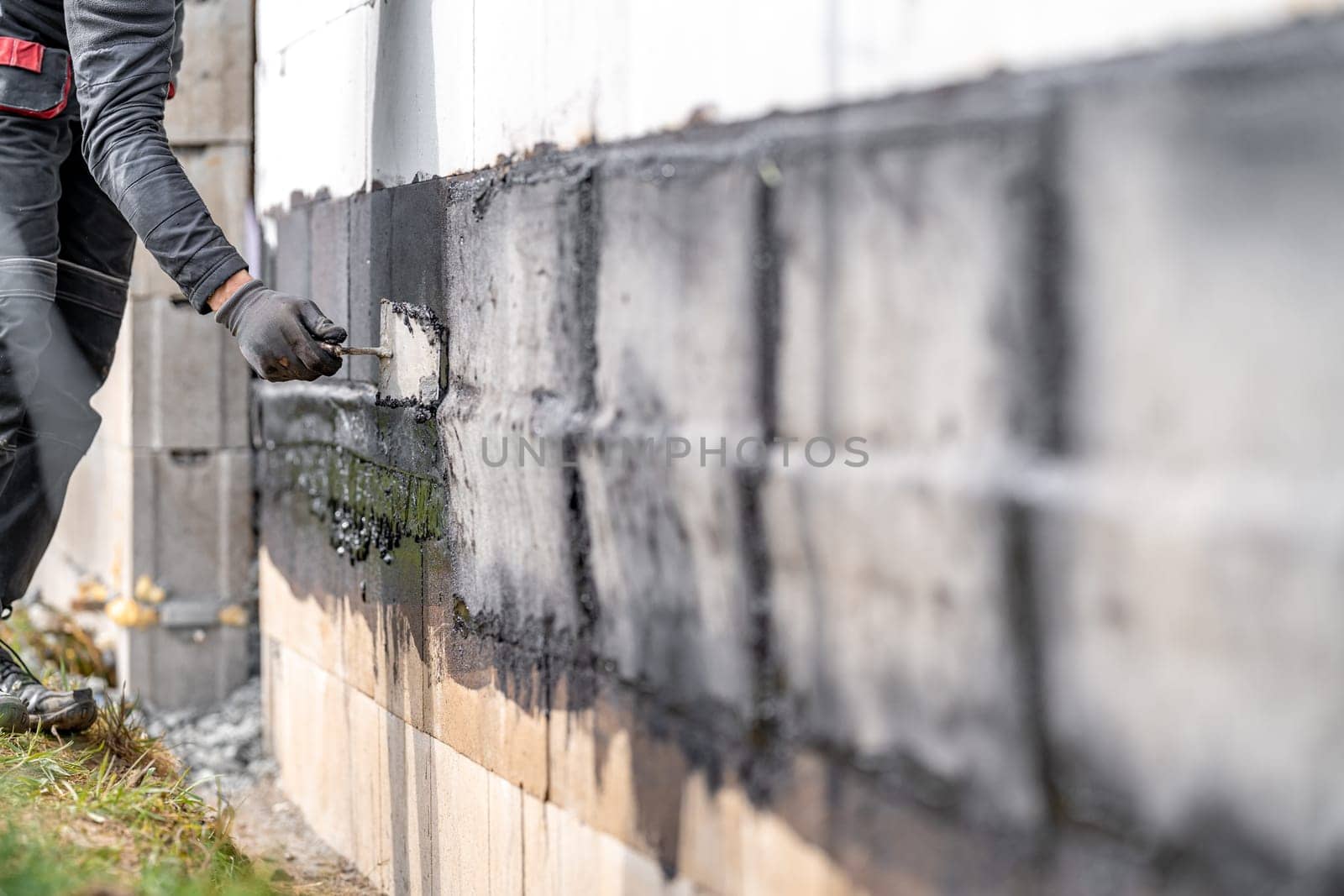 waterproofing of the wall with a covered asphalt belt during the construction of the house.