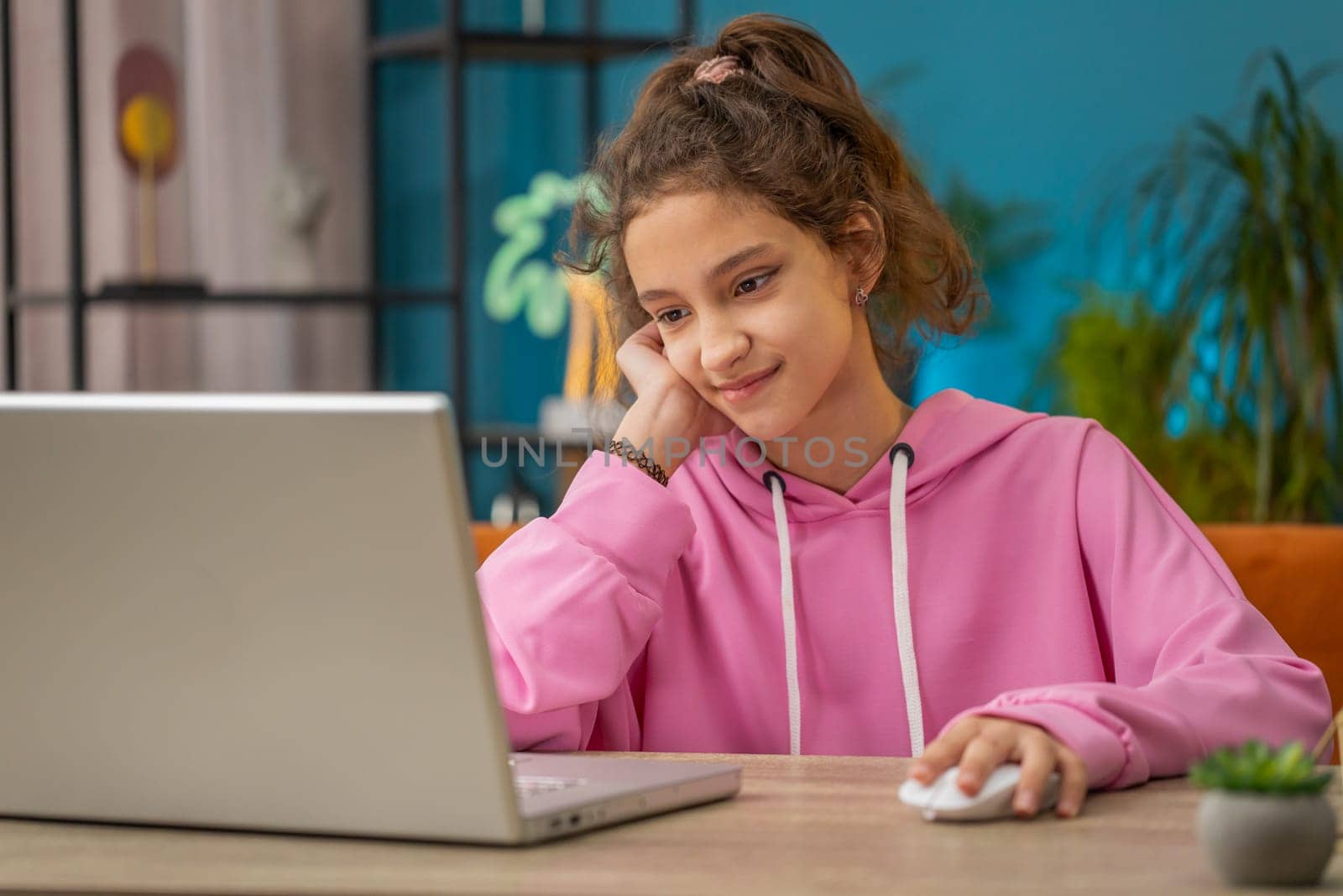 Caucasian preteen school girl using laptop for online lesson, doing homework. Distance learning education. Young child, kid at home workplace sitting at the table. Video call by webcam on internet