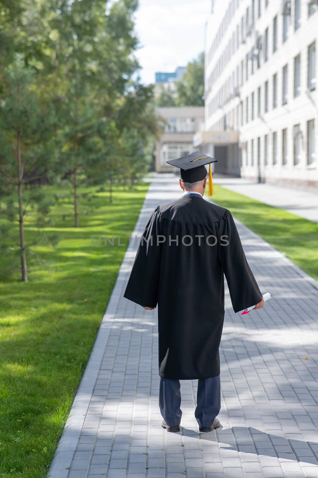 Rear view of an elderly man in a graduation gown