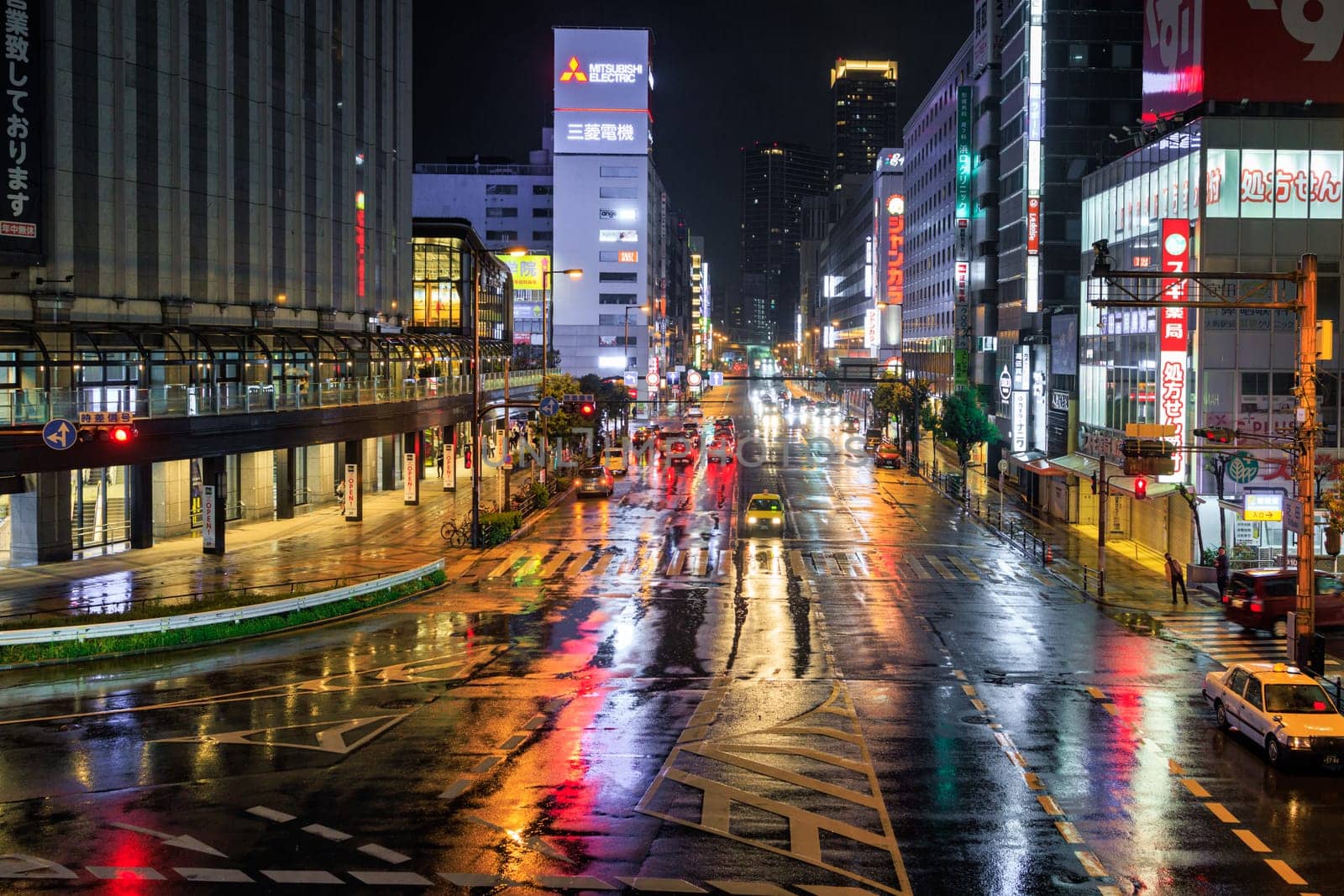 Osaka, Japan - April 12, 2023: Lights reflect off wet streets in downtown Osaka on rainy night. High quality photo