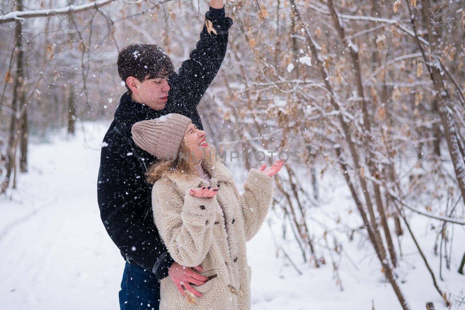 A young couple walks in the park in winter. Guy and girl hugging outdoors