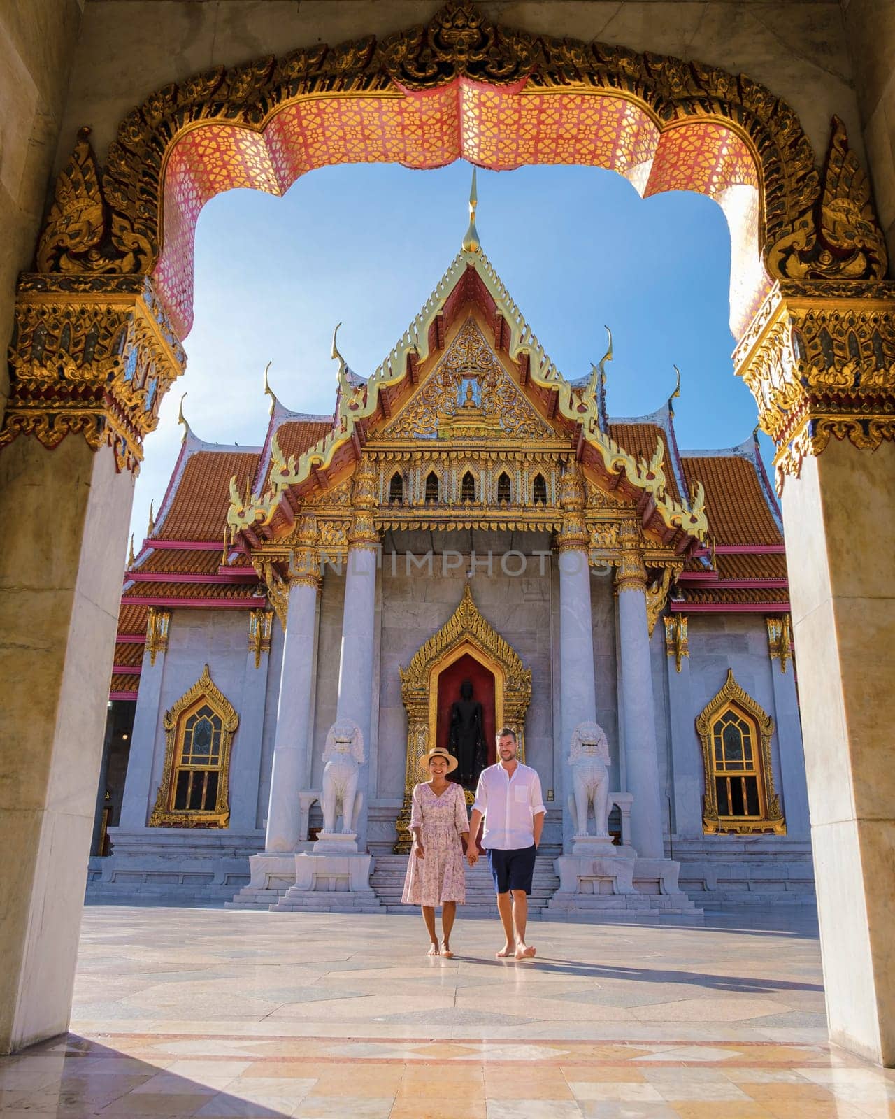 A couple of men and women visit Wat Benchamabophit temple in Bangkok Thailand, The Marble temple in Bangkok. Asian woman with a hat and European men visiting a temple in Bangkok