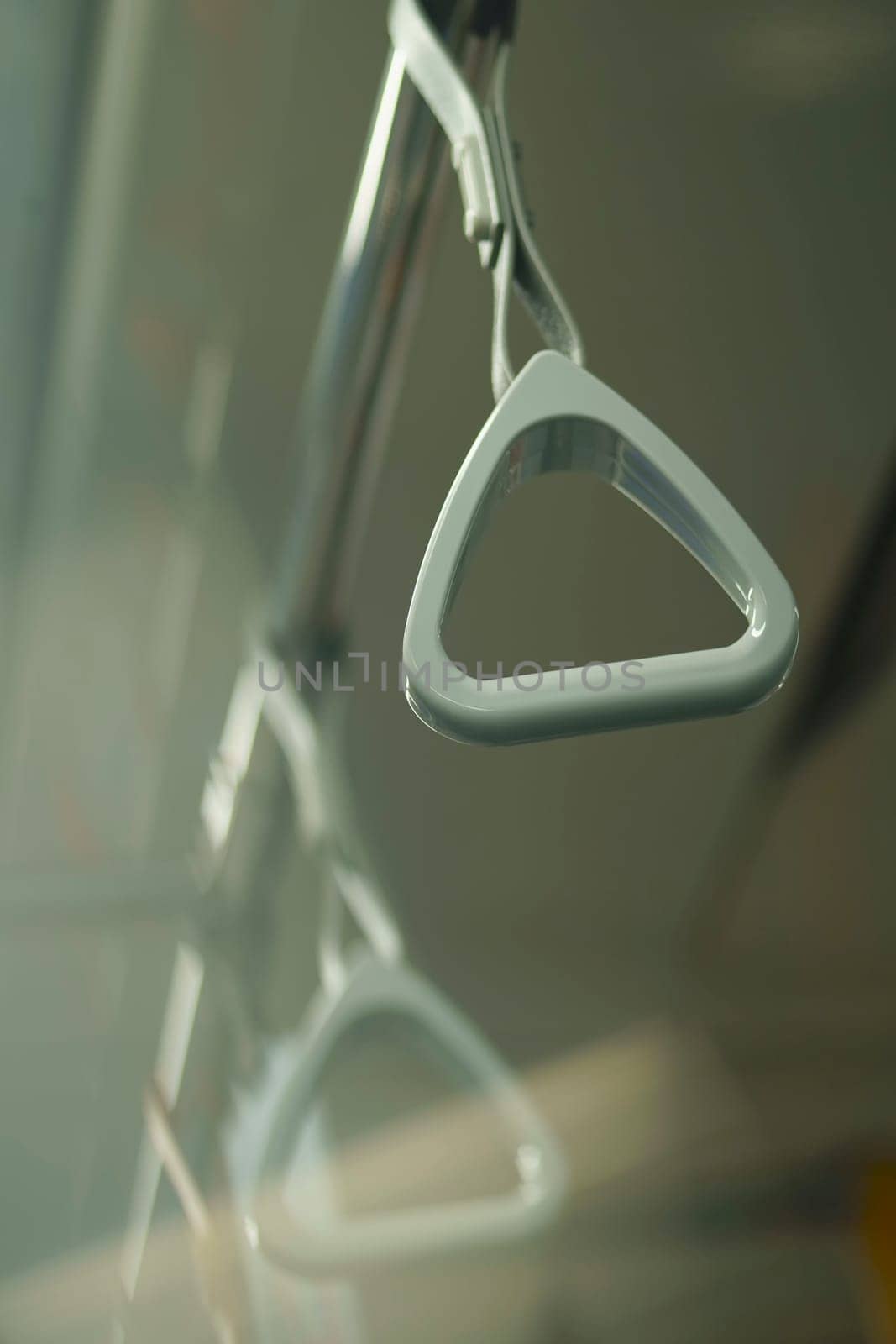 Close up and selective focus of grey triangle handle bar in the train of MRT Jakarta, Indonesia. Blurred background with copy space.