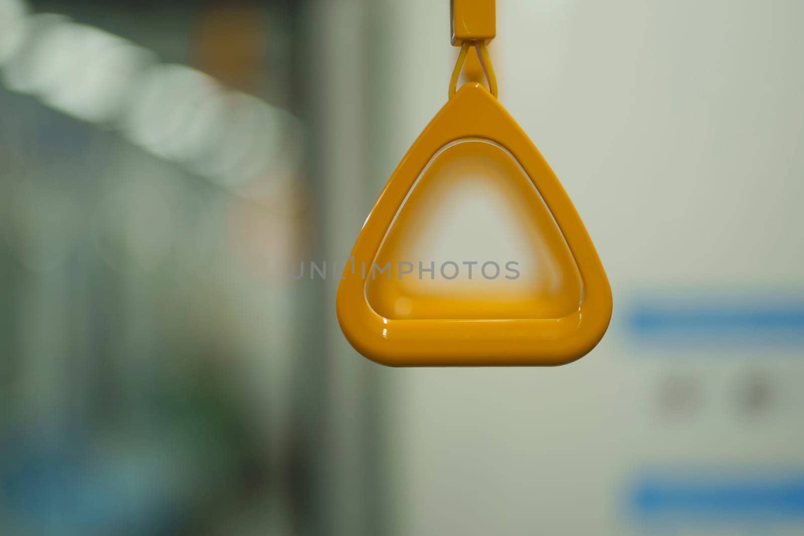 Close up and selective focus of yellow triangle handle bar in the train of MRT Jakarta, Indonesia. Blurred background with copy space.