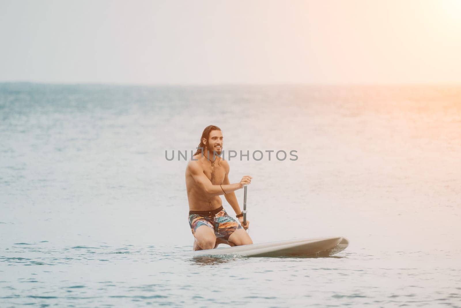 Sea woman and man on sup. Silhouette of happy young woman and man, surfing on SUP board, confident paddling through water surface. Idyllic sunset. Active lifestyle at sea or river