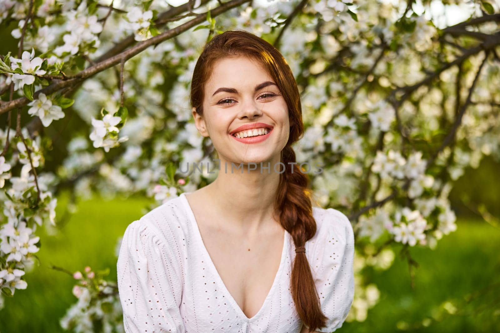 Portrait of happy woman in blooming orchard. Beautiful woman enjoy in nature in spring. High quality photo