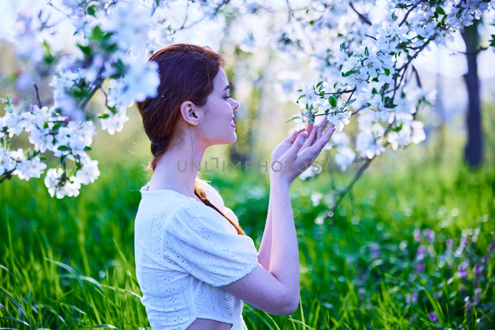 portrait of a woman standing next to a flowering tree in cold color. High quality photo