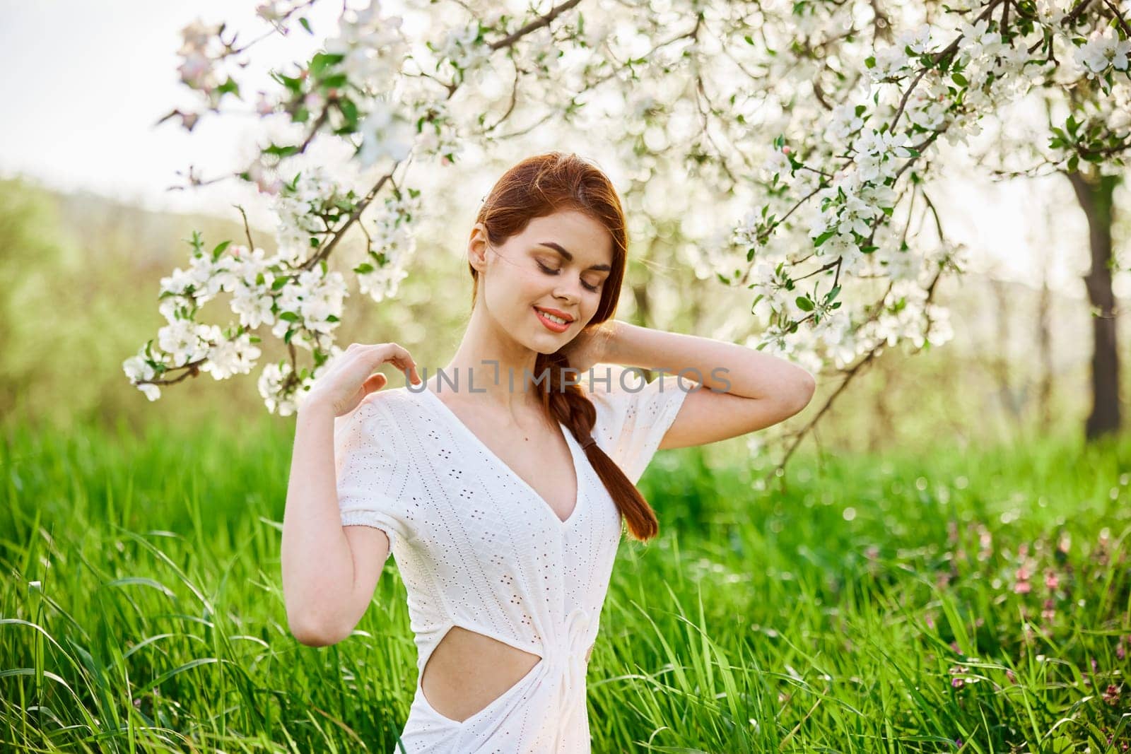 Young beautiful woman in a white dress posing in garden by Vichizh