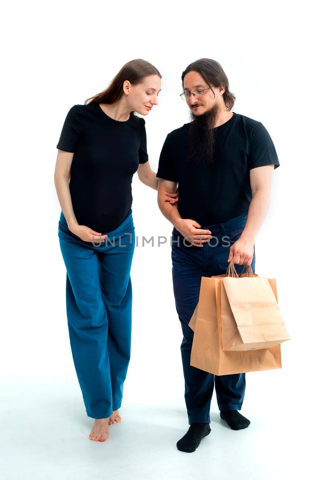 Portrait happy young pregnant woman and her husband with shopping bags and touching her big belly isolated on white background. Pregnancy shopping concept happy young family with shopping bags