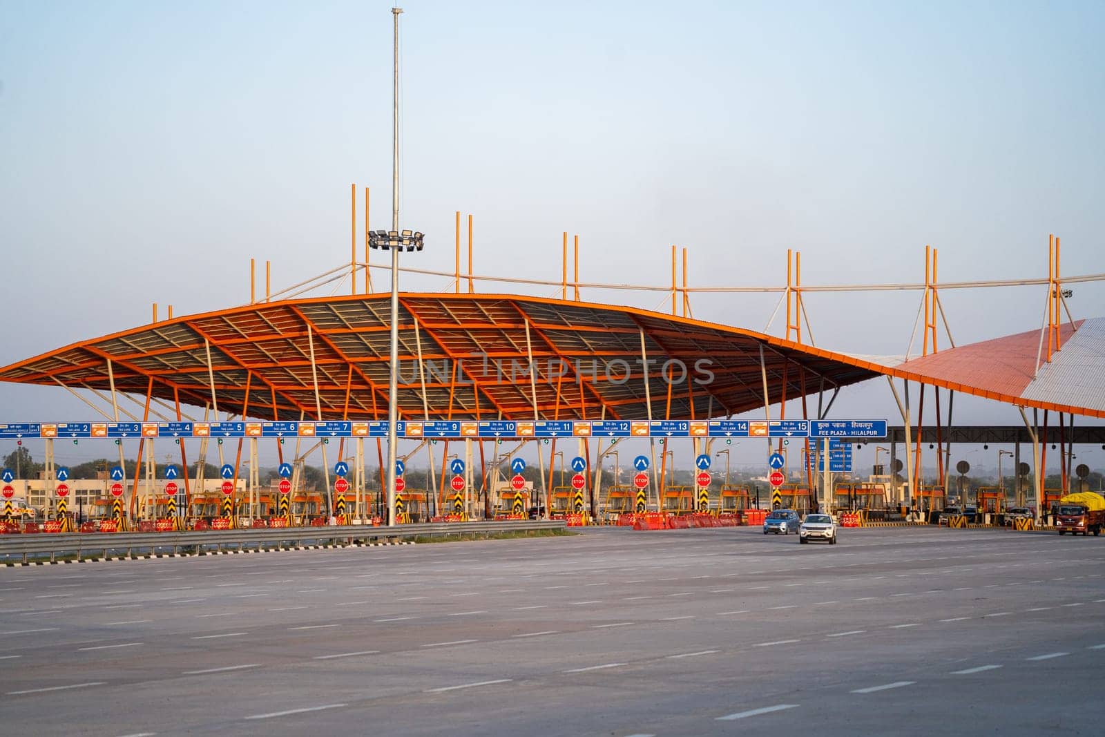 huge toll booth set up on delhi, jaipur, surat, baroda, mumbai highway with cars, trucks and other vehicles coming out after paying through FASTag RFID payment by Shalinimathur