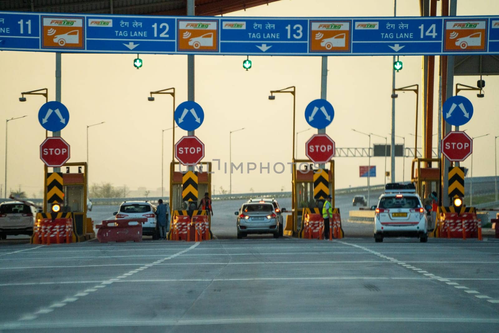 huge toll booth set up on delhi, jaipur, surat, baroda, mumbai highway with cars, trucks and other vehicles coming out after paying through FASTag RFID payment by Shalinimathur