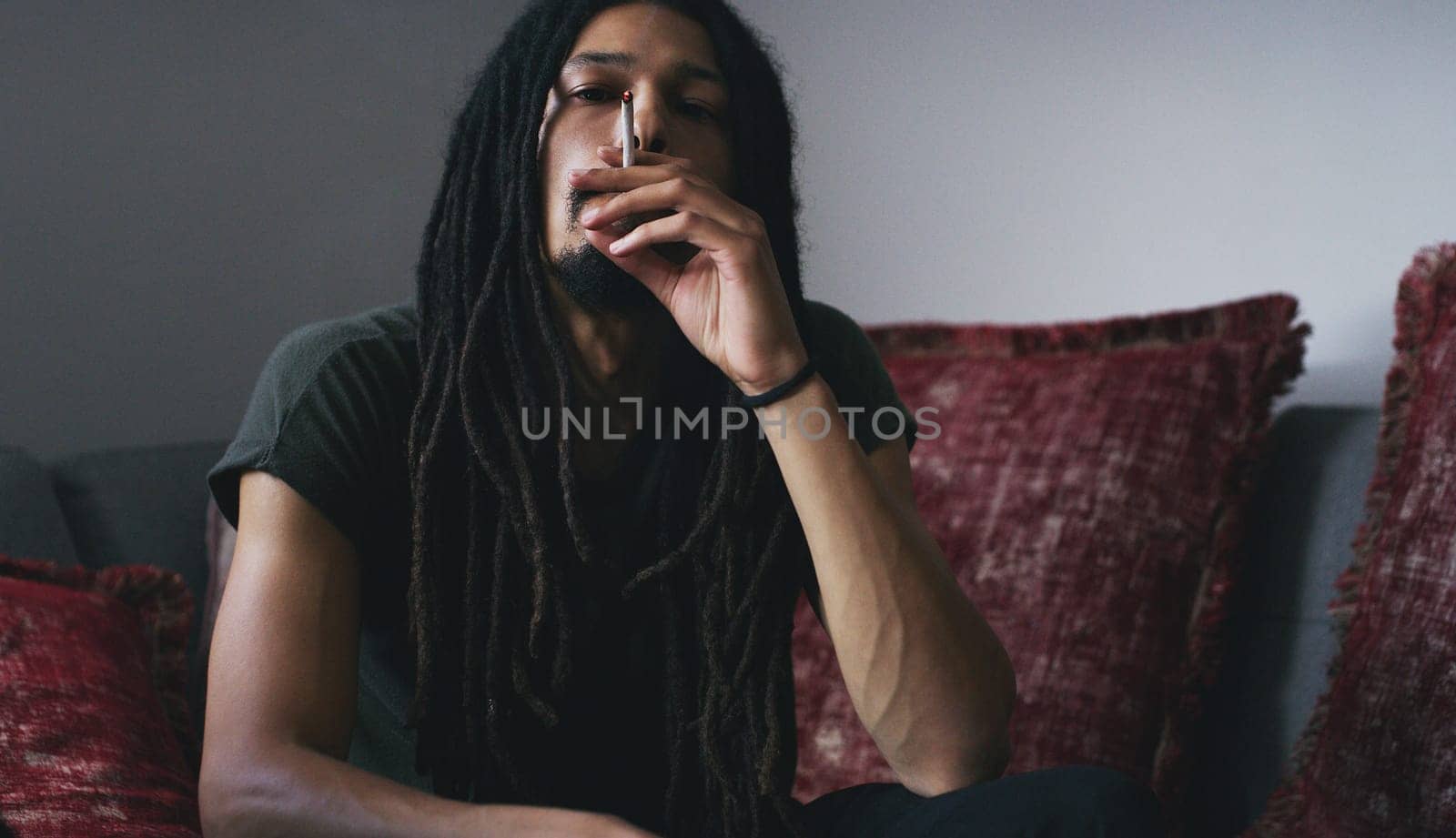 Its more of a lifestyle for me. a young man smoking a marijuana joint at home