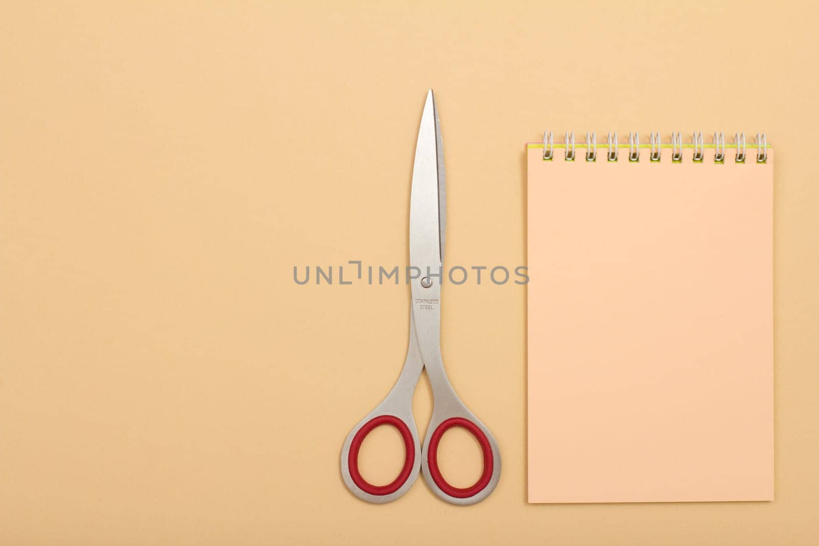 School supplies. Notebook and scissorson on beige background. Top view with copy space. Back to school concept. Pastel colors.