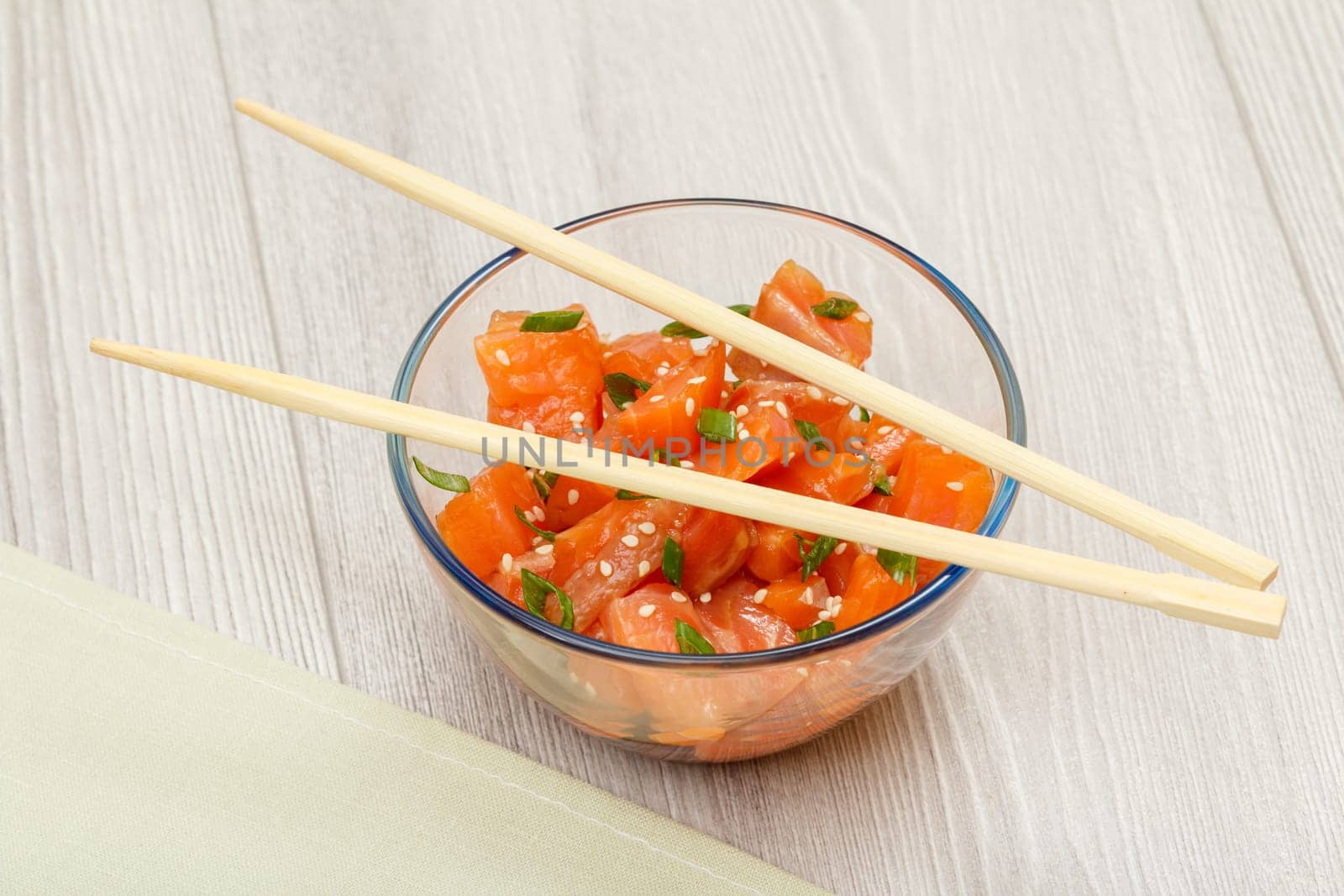 Hawaiian salmon poke with green onions and sesame seeds in glass bowl. by mvg6894
