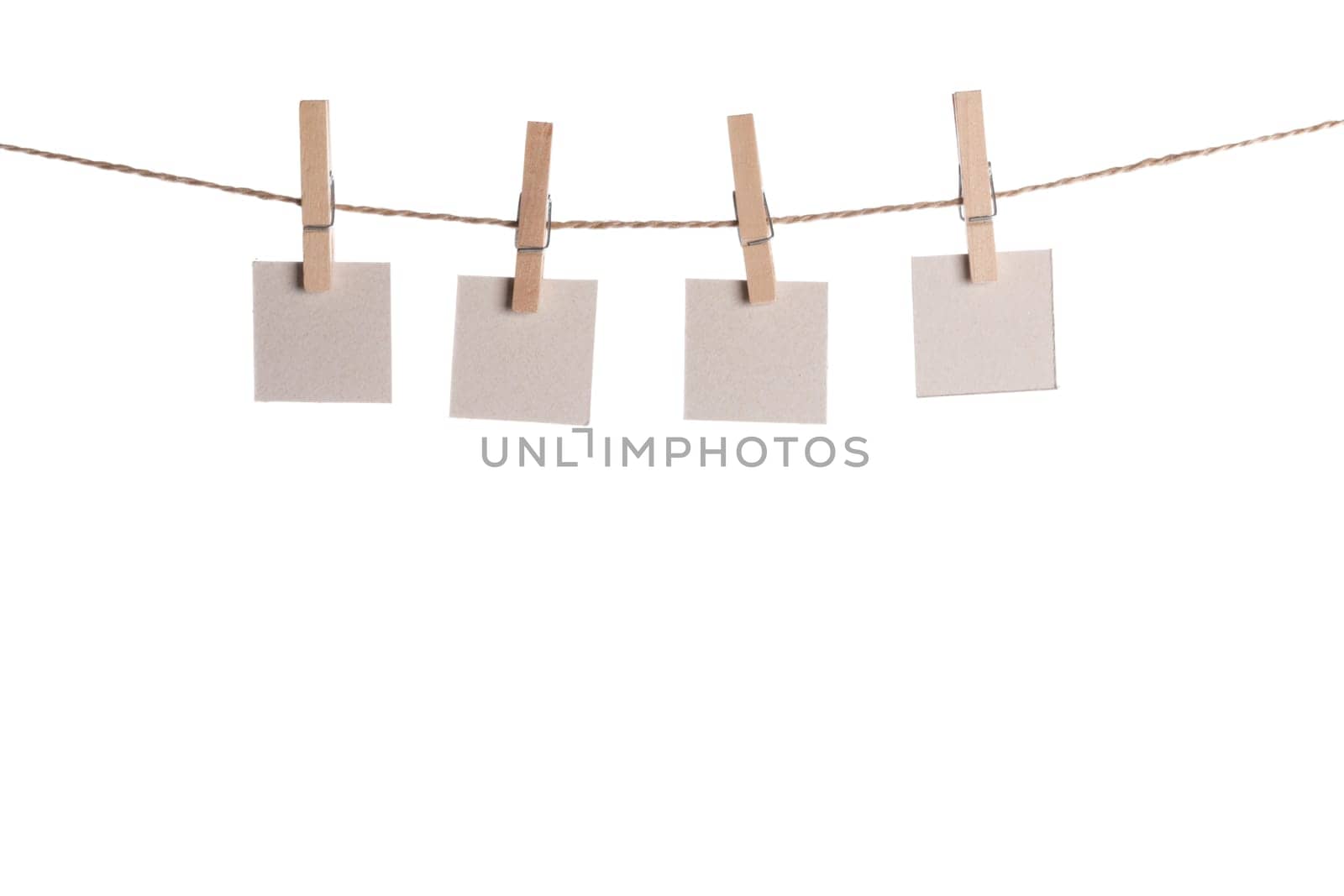 Set of four blank paper notes held on a string with clothespins isolated on white background
