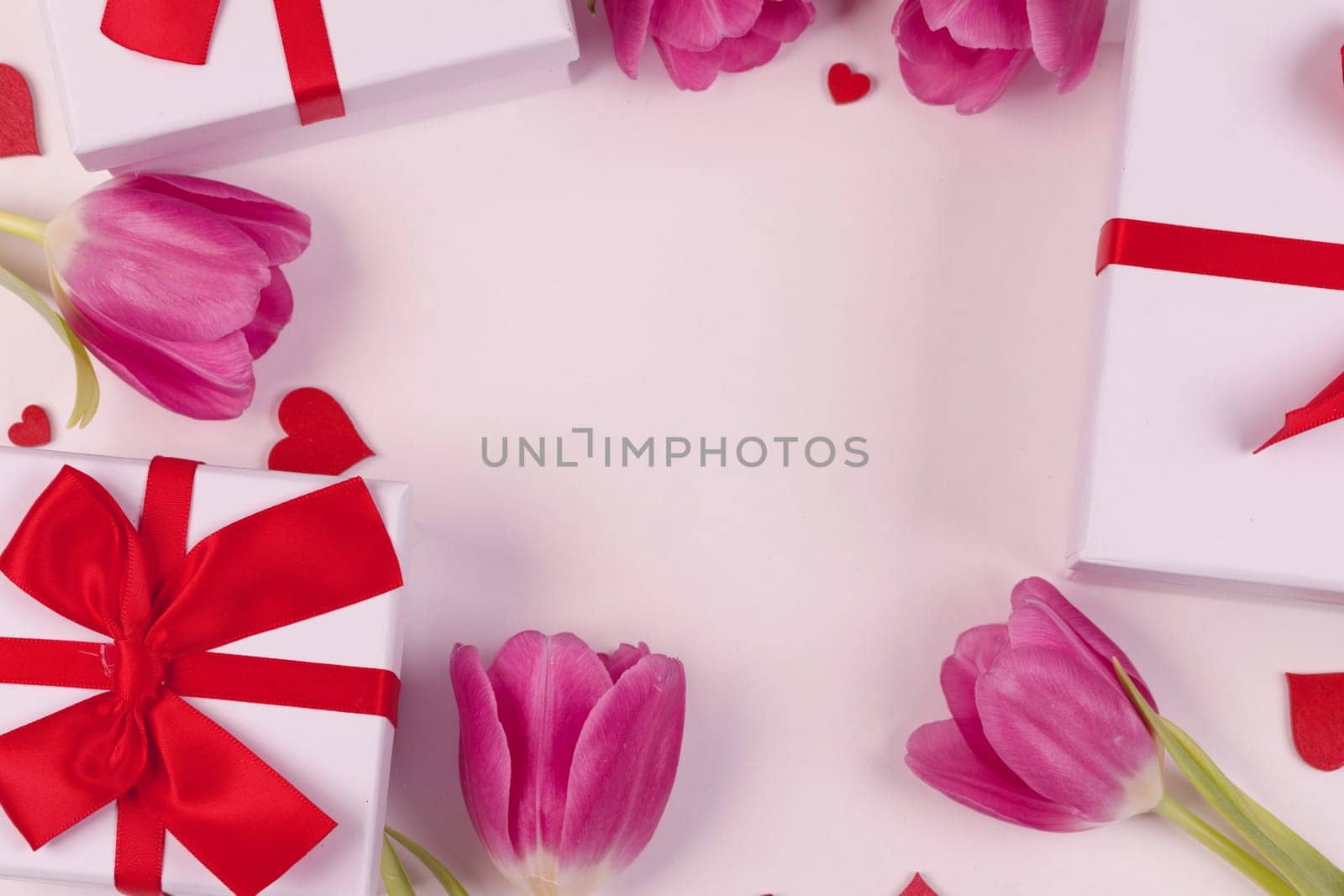 Pink tulip flowers gifts and red hearts composition on pink background top view with copy space. Valentine's day, birthday, wedding, Mother's day concept. Copy space