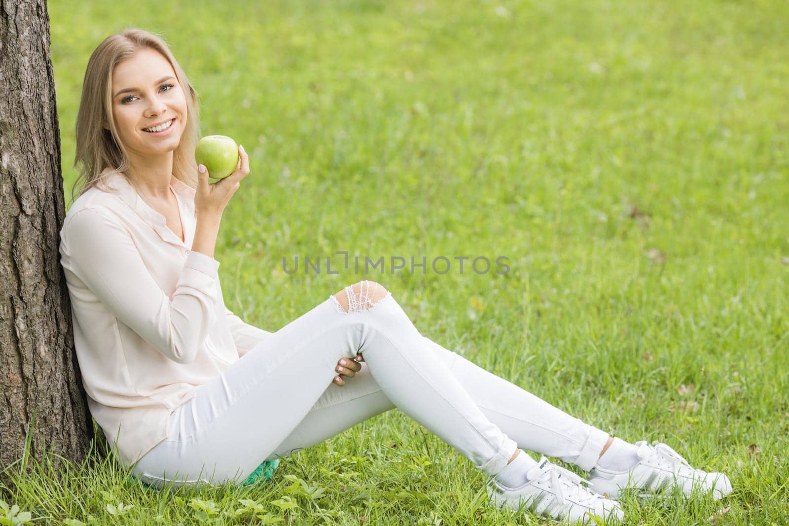 Woman sitting on green grass eating an apple, healthy eating healthcare concept