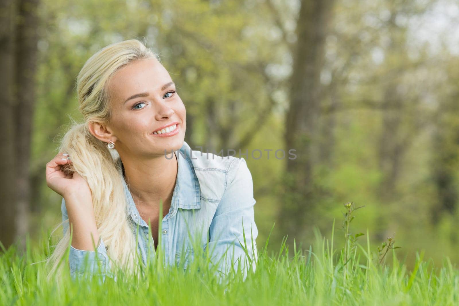 Blonde woman laying grass by Yellowj