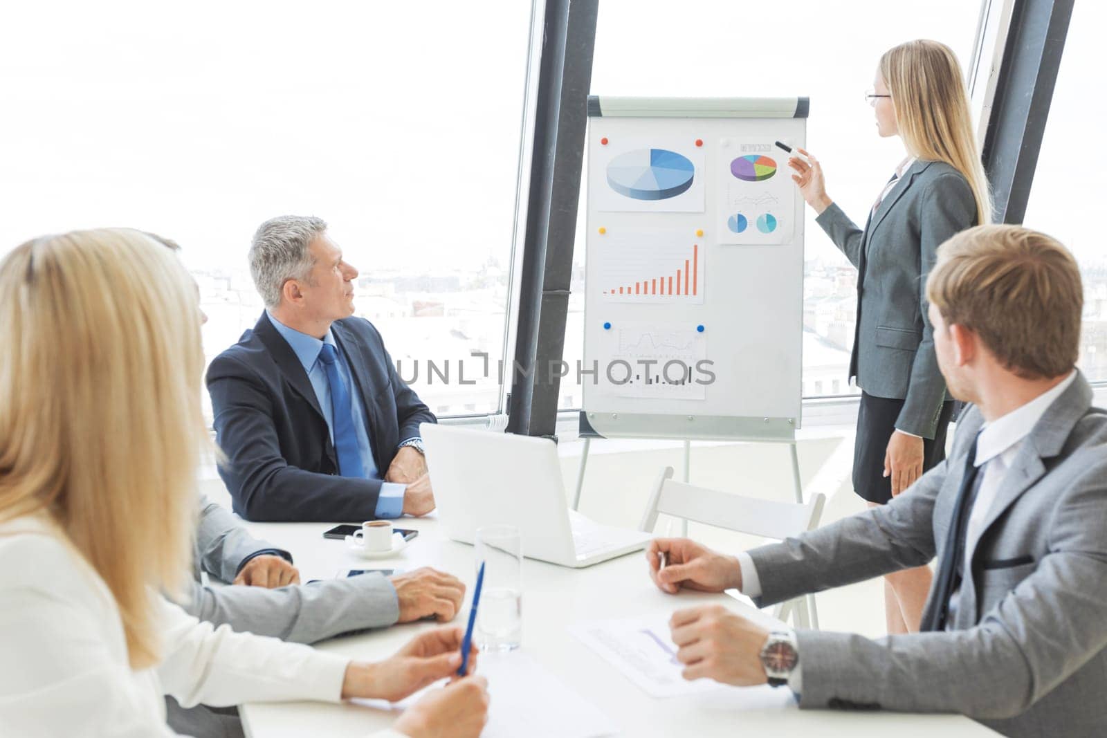 Business people at presentation in office. Businesswoman presenting financial reports on whiteboard.