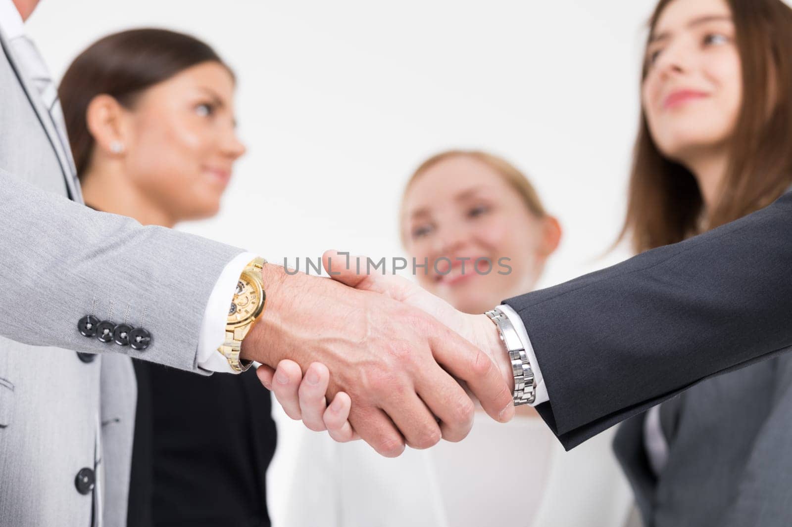 Business people shaking hands, colleagues on background