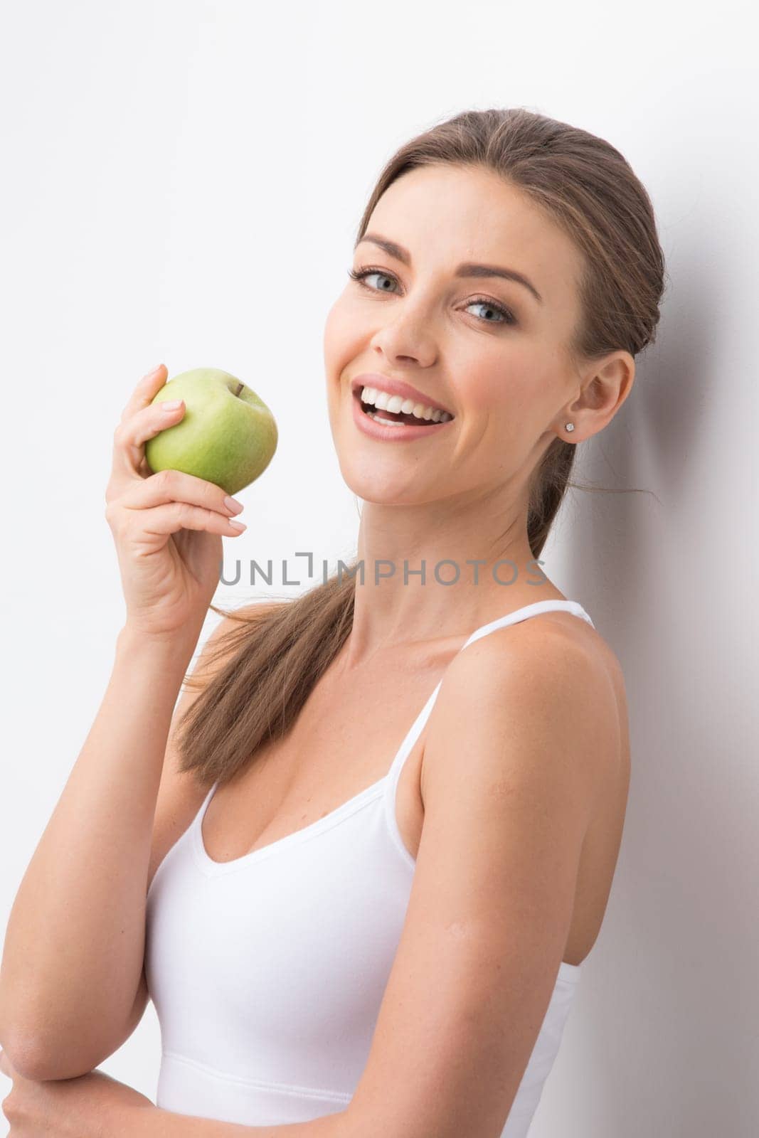 Beautiful smile, white strong teeth. Young woman with snow-white smile holding green apple