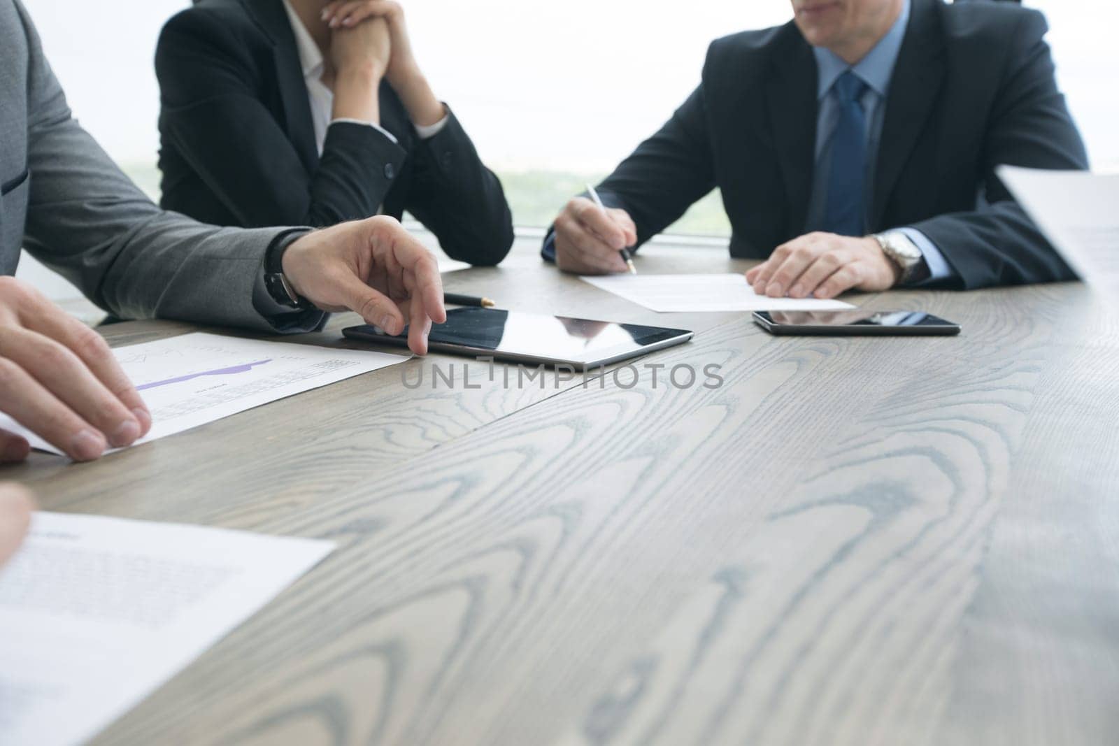 Abstract Image of business people meeting at office table with smart phone and digital tablet and coworkers working in the background
