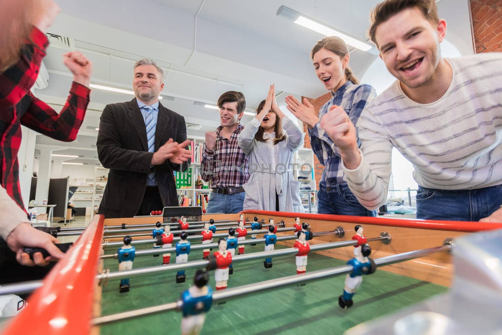 Employees playing table soccer indoor game in the office during break time