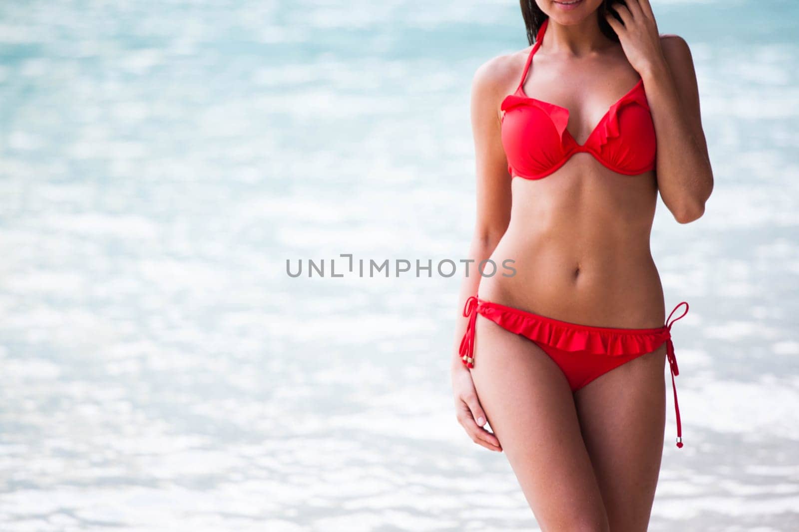 Pretty beautiful woman in white swimwear bikini posing in blue sea water