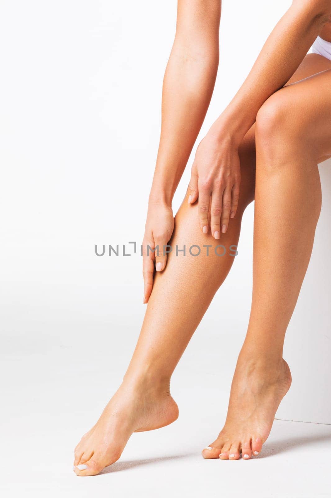 Young beautiful woman touching legs on white background